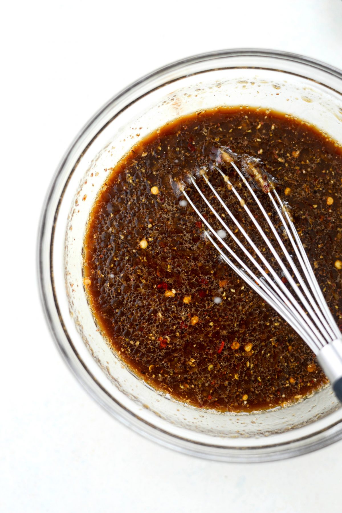 close up of Kung Pao sauce in bowl with whisk.