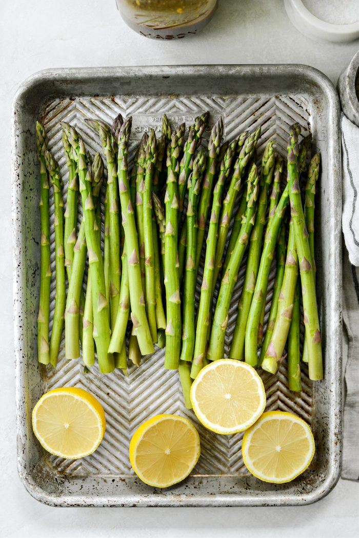 trim asparagus, cut lemons into halves and place on a rimmed baking sheet