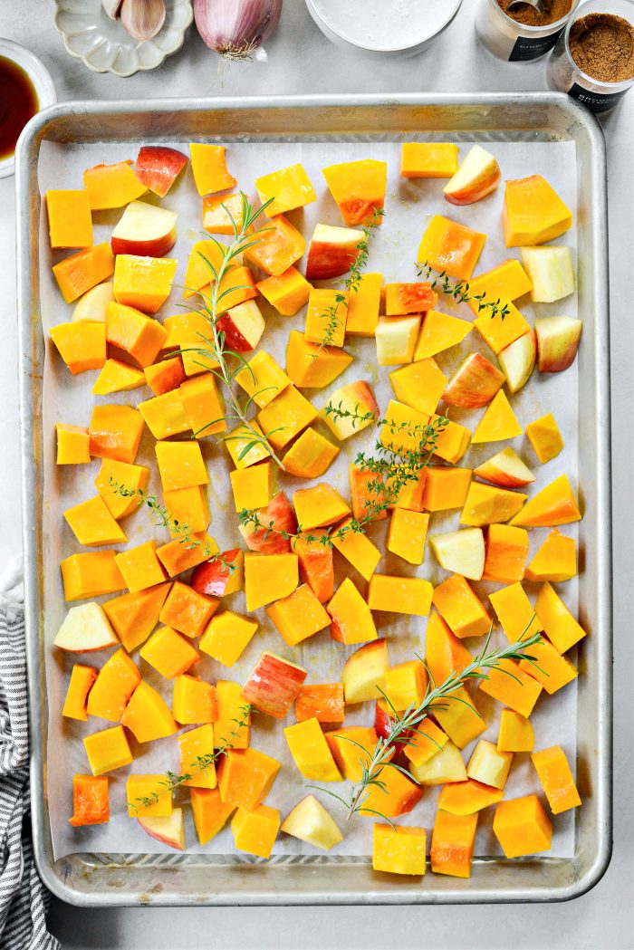 butternut squash, apples and herbs on baking sheet